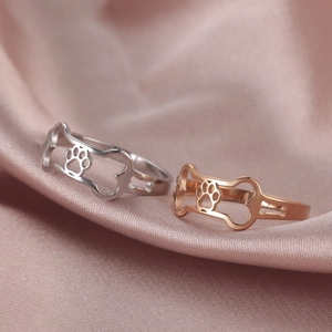 Hollow dog bone and paw print rings in silver and rose gold on pink silk fabric