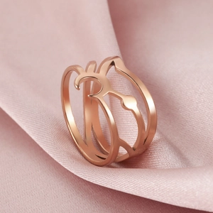 Macro view of triple-layered rose gold cat silhouette ring on pink silk fabric