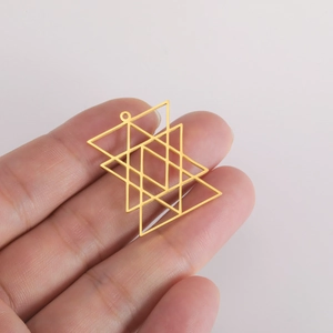 Golden geometric hollow star pendant accessory held in hand on gray background