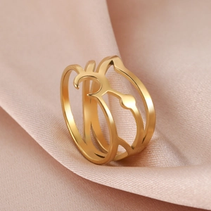 Macro shot of gold-plated cutout ring with geometric curves on pink satin fabric