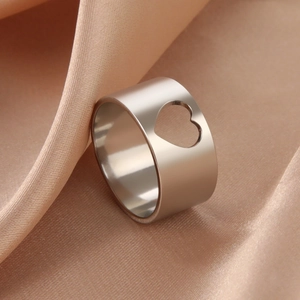 Polished silver heart hollow cutout band ring displayed on champagne silk fabric