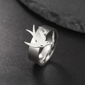 Detalle de cerca de un anillo de acero inoxidable plateado con dije de pájaro golondrina