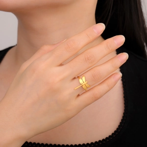 Primer plano de un anillo de libélula dorada en la mano, mostrando detalles elegantes