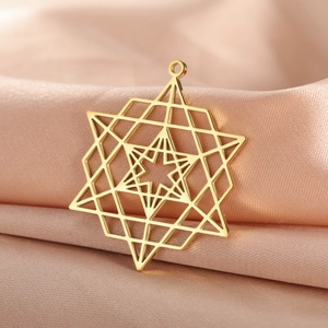 Détail d'un pendentif étoile géométrique plaqué or 18K sur un tissu en soie satinée