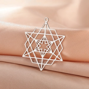 Détail macro du pendentif hexagramme géométrique argenté sur un tissu en soie champagne