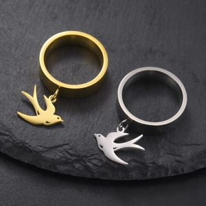 Primer plano detallado de anillos de acero inoxidable oro y plata con colgante de golondrina
