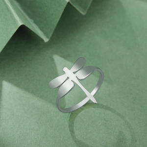 Anillo de libélula en acero inoxidable con alas mate sobre fondo verde Morandi