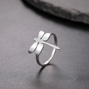 Detalle macro de un anillo de libélula minimalista en plata sobre fondo oscuro mate