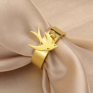 Vista macro de un anillo ancho de acero dorado con un colgante de golondrina elegante