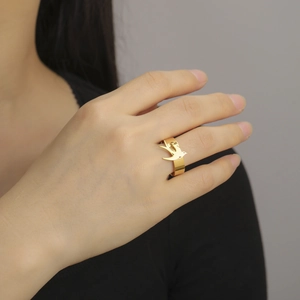 Primer plano de un anillo de golondrina dorado con acabado de espejo lucido en la mano