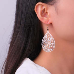 Gros plan de boucles d'oreilles vintage en forme de goutte blanche ajourée portées par un mannequin