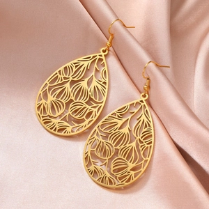 Vue détaillée de boucles d'oreilles dorées en filigrane sur un tissu en soie champagne chic