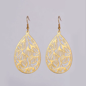 Détail de boucles d'oreilles pendantes dorées avec motifs de feuilles ajourées
