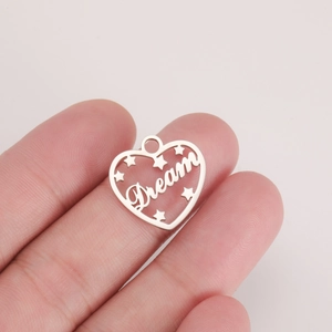 Macro shot of silver heart Dream pendant with star detail held for size reference