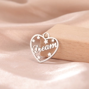 Detailed view of silver heart pendant with Dream engraving and cutout stars on silk