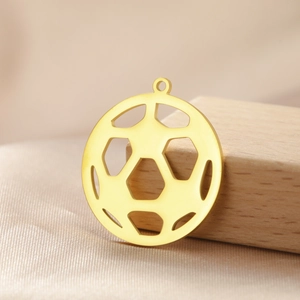 Macro shot of a hollow golden stainless steel soccer ball pendant on wooden props