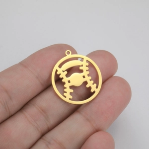 Macro shot of gold stainless steel baseball charm pendant held in hand for scale