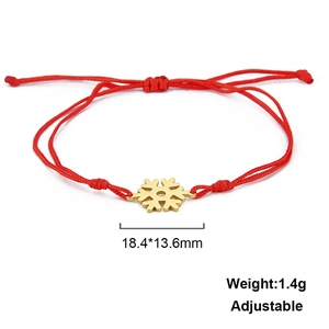 Detail view of golden snowflake charm on red braided rope bracelet with adjustable cord