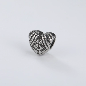 Macro shot of retro silver stainless steel heart charm with detailed wing feather texture