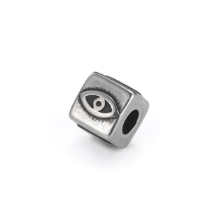 Détail macro d'une perle cubique en acier inoxydable avec motif œil grec et fini vieilli