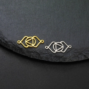 Symmetric geometric stainless steel connectors with gold and silver finishes on black slate