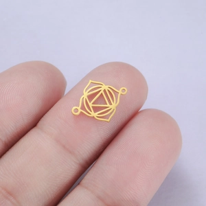 Close-up of golden stainless steel chakra connector held on fingertip for size