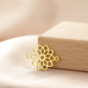 Detailed view of a gold mandala chakra connector on a wood block with silk fabric