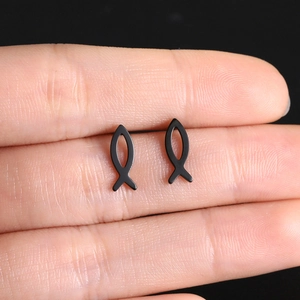 Macro shot of minimalist black titanium small fish stud earrings on a finger