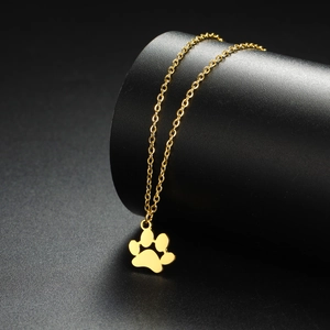 Close-up of a polished golden cat paw pendant on a fine metal chain over a black background