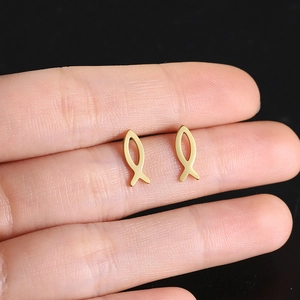 Gold titanium steel ichthys fish stud earrings held by hand for scale on black background