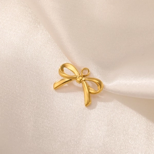 Polished gold stainless steel bow pendant on silk background for DIY jewelry making