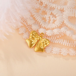Macro shot of a matte gold bow pendant with round ring on white lace and feather background