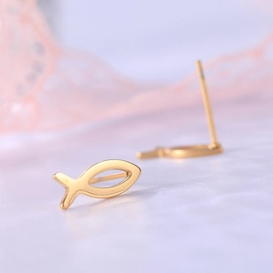 Macro view of gold Ichthys fish stud earrings on purple velvet with lace detail