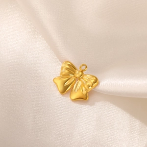 Macro shot of gold satin bow pendant on silk, minimalist DIY jewelry accessory charm