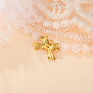 Close-up of golden bow pendant with mounting ring on soft lace and feathers