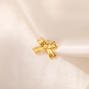 Macro detail of a matte gold bow pendant with a round ring on beige silk background