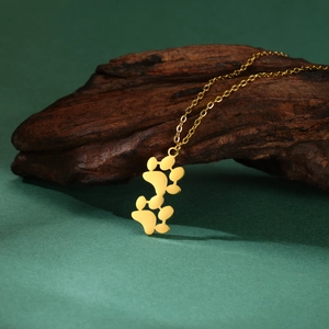 Dettaglio di collana dorata in acciaio inox con ciondolo a doppia zampa su legno scuro