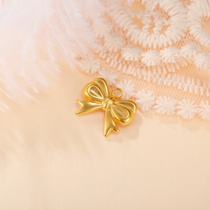 Detail of a matte gold bow pendant on white feathers and lace for DIY jewelry making
