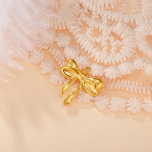 Macro shot of a golden bow pendant for DIY jewelry on white lace and feather background