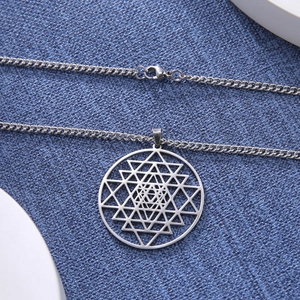 Detailopname van een zilveren Sri Yantra geometrische hanger aan een fijne schakelketting