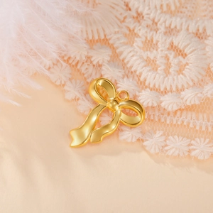 Close-up of a polished gold bow pendant with round ring on an elegant lace background