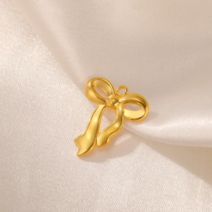 Macro detail of golden stainless steel bow pendant on champagne silk fabric background