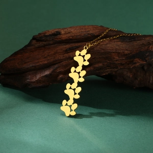 Dettaglio macro della collana dorata con impronte di zampe su fondo in legno