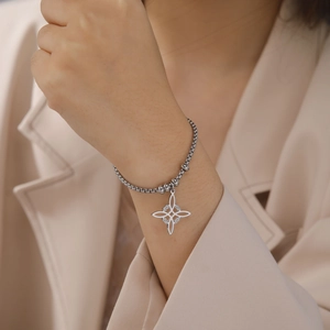 Detalle de una pulsera de cuentas de acero inoxidable con nudo de bruja en una muñeca mujer