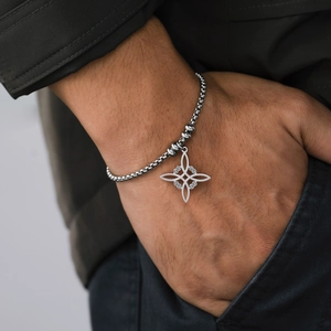 Primer plano del colgante de nudo de bruja de acero inoxidable en pulsera de cadena