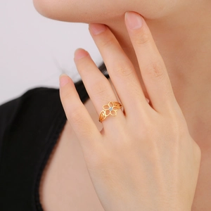 Detail van gouden bloemring met centrale zirkoon aan de vinger van een vrouwelijk model