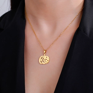 Gold hollow pumpkin necklace with moon and bats worn by a model on a black blazer