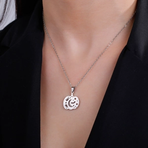 Minimalist stainless steel pumpkin necklace with moon and star cutout on black blazer