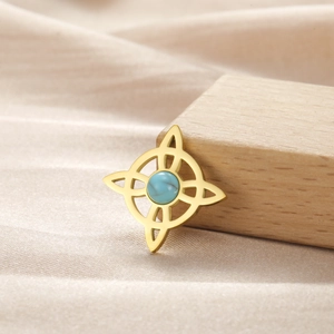 Detalle de colgante de estrella dorada con piedra turquesa sobre fondo de seda suave