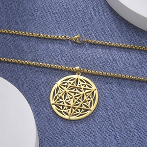 Vue détaillée du pendentif Merkaba doré posé sur un tissu texturé bleu marine élégant